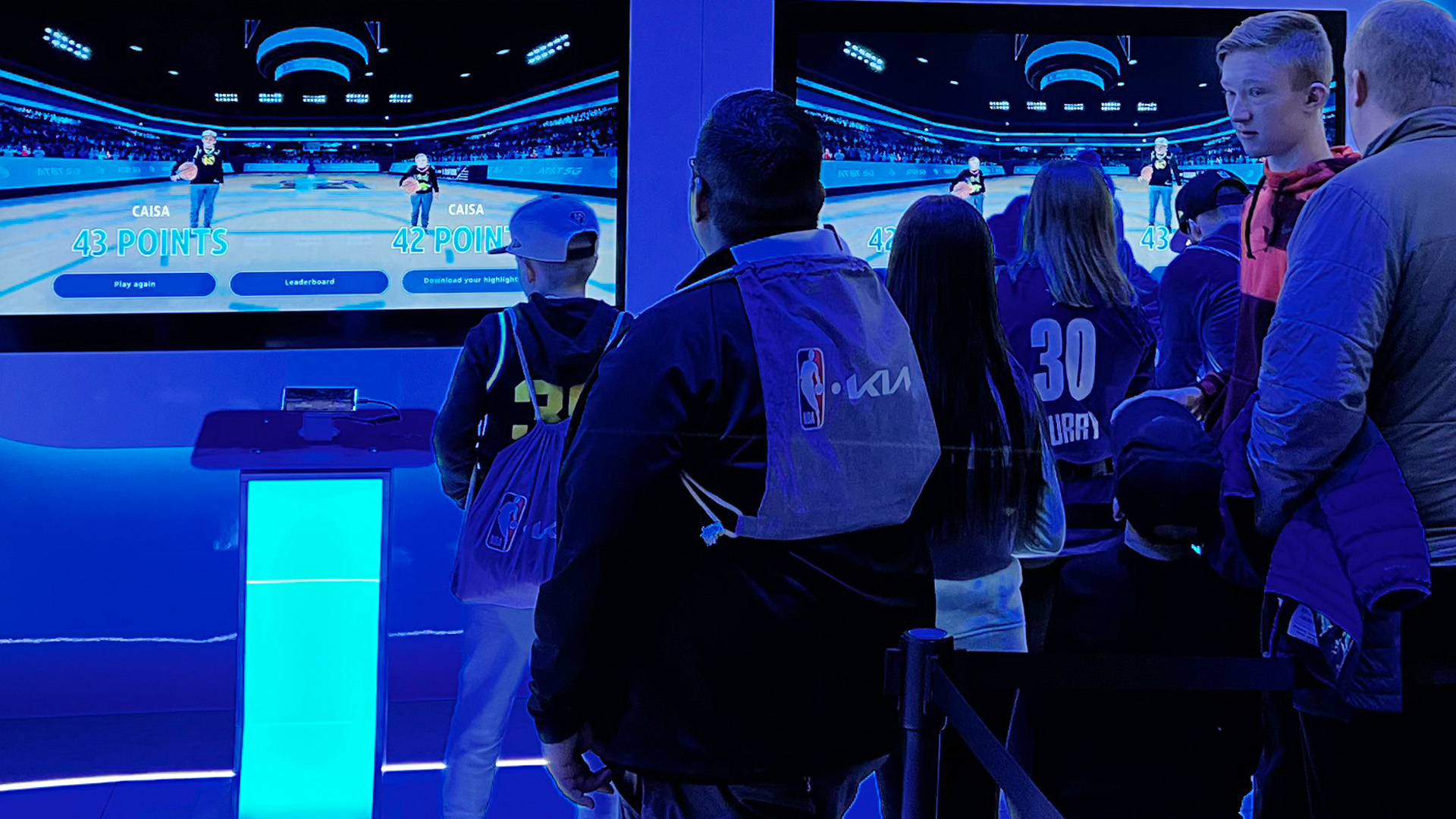 A crowd watching two fans playing Dunk Champion against each other in the AT&T NBA All-Star Playmaker Arcade.